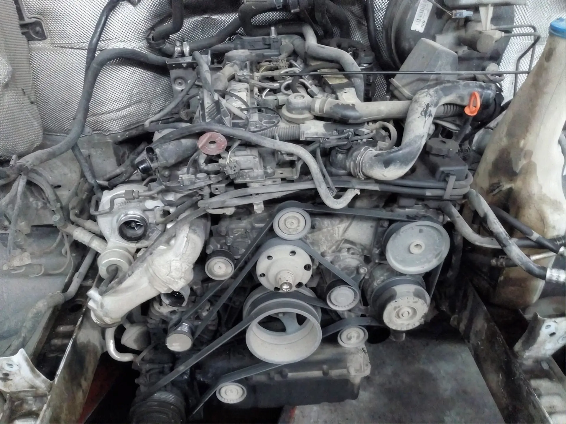 Primer plano del motor de un vehículo con correas y poleas a la vista